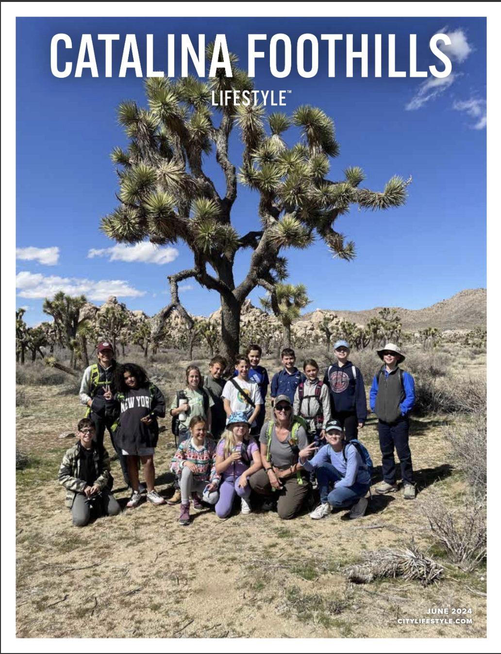 Cover of Catalina Foothills Lifestyle magazine cover with large Joshua tree cactus with a group of Outdoor Adventure program kids and the two guides standing at the base. 